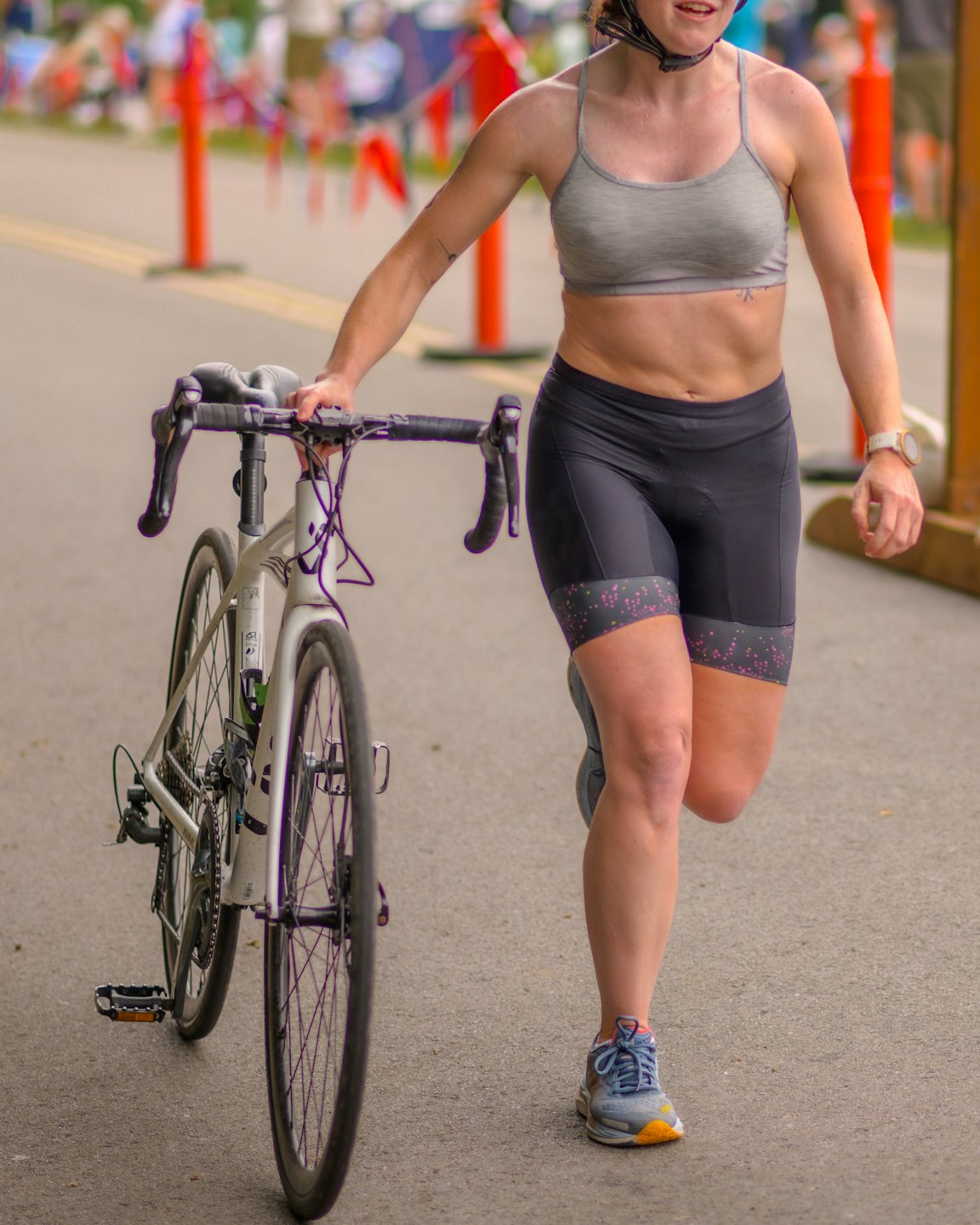 Triathlete running while pushing her bicycle in a race transition.