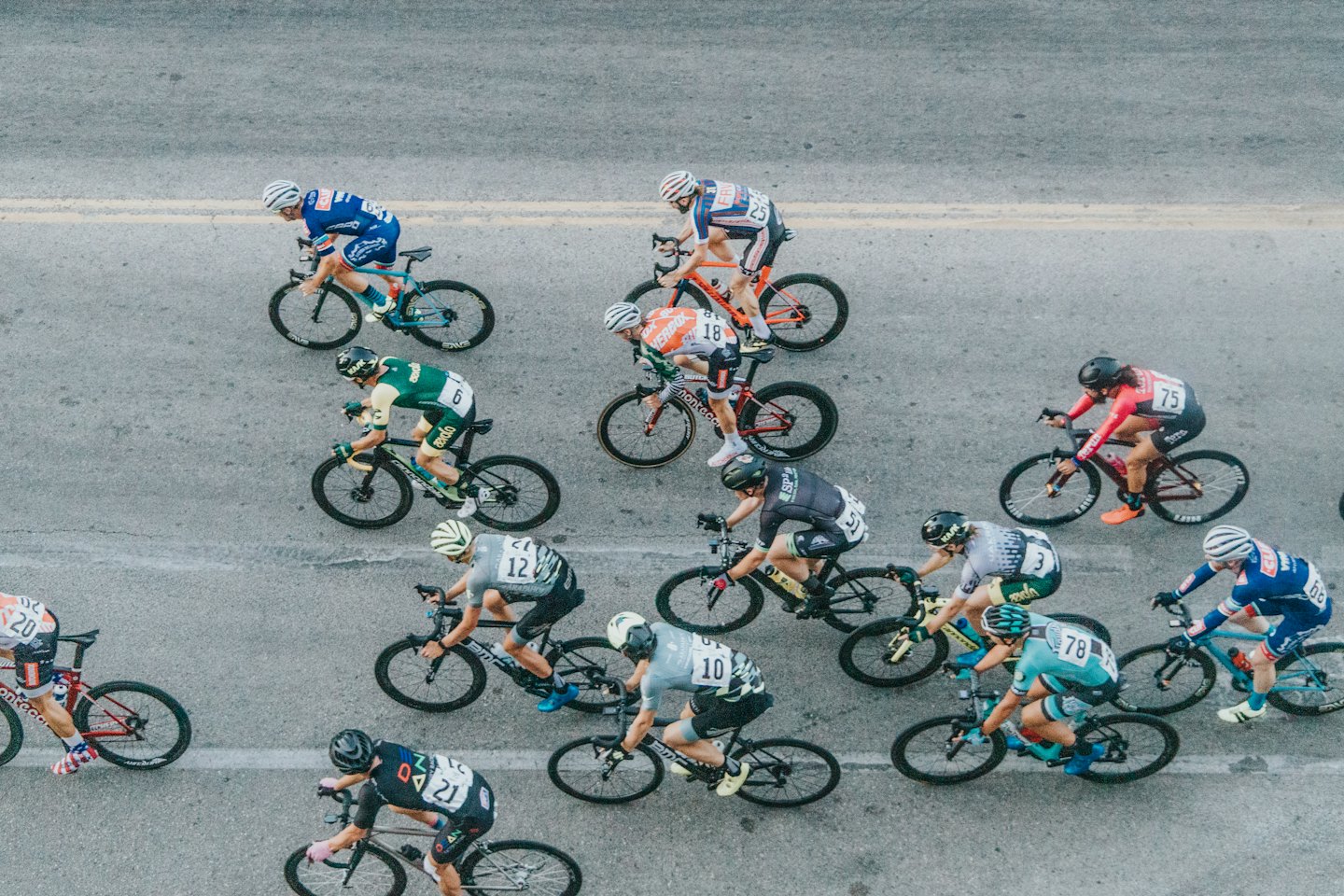 Cyclists in jerseys racing closely together on an asphalt road.