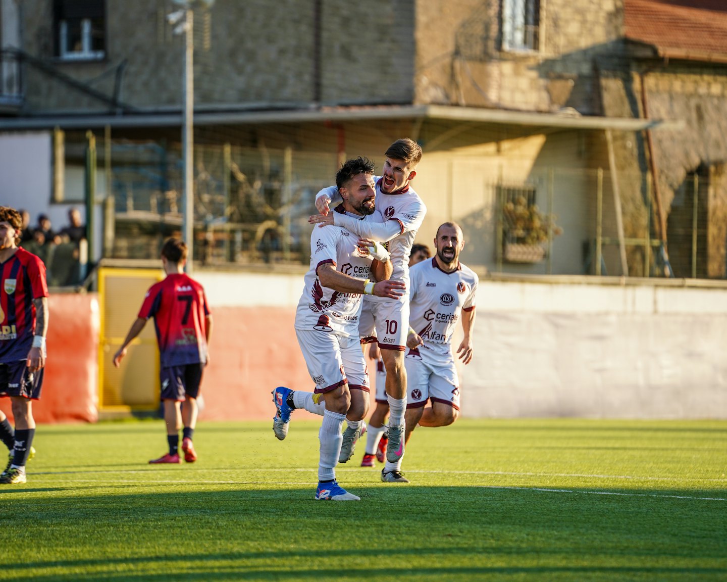 Two soccer players celebrate joyfully on a sunny green field.